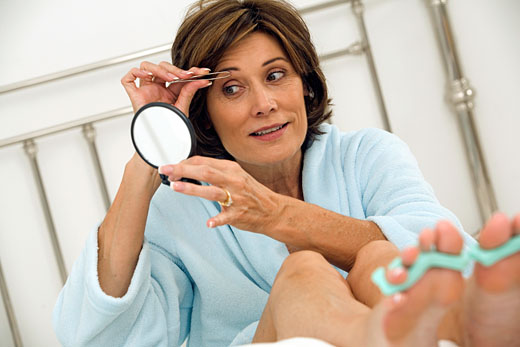 mature woman plucking her eyebrows